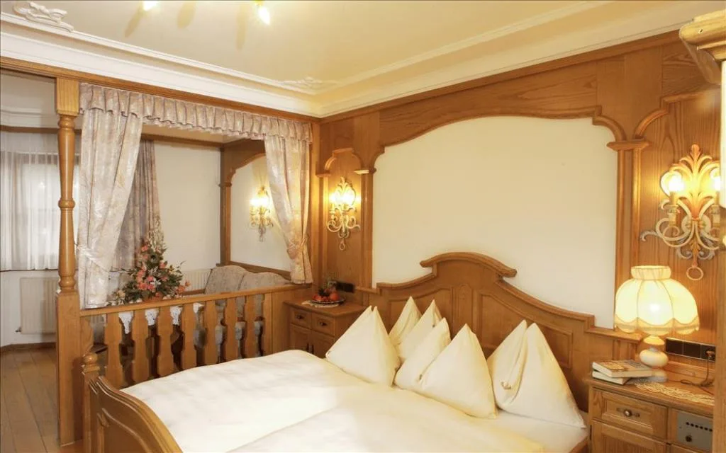Camera da letto in stile alpino con letto a baldacchino e boiserie in legno
