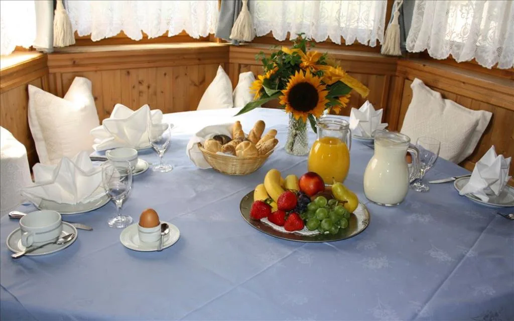 Tavolo per la colazione apparecchiato con frutta fresca, pane, succo e girasoli