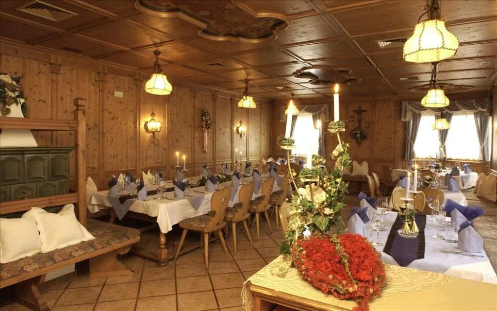 Sala da pranzo tradizionale con boiserie in legno, tavoli apparecchiati e stufa in maiolica
