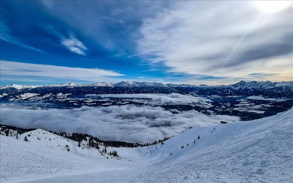Panorama invernale delle montagne innevate con mare di nuvole nella valle