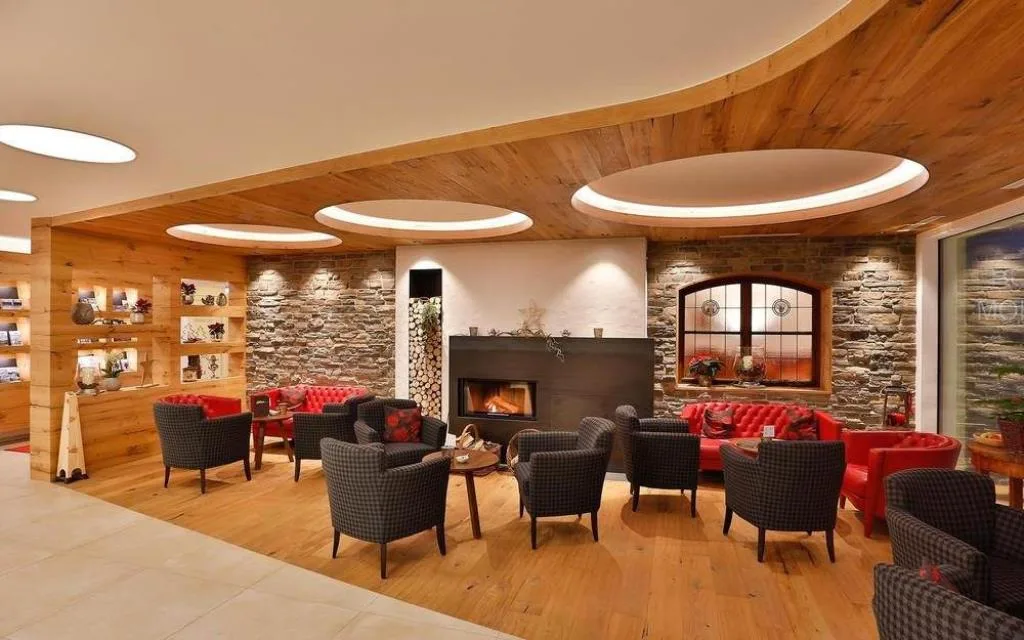 Lounge con camino, poltrone e pareti in pietra e legno