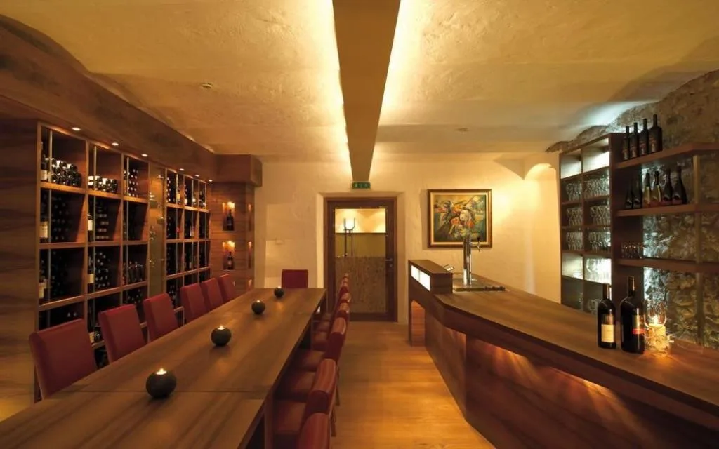 Cantina dei vini con scaffali in legno, tavolo e bottiglie