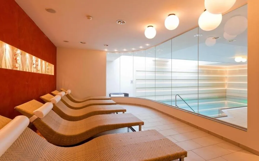 Zona relax con lettini in vimini accanto alla piscina interna