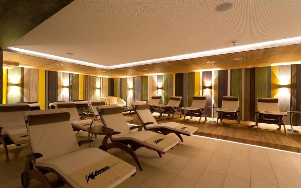 Sala relax con lettini e parete a strisce colorate illuminata