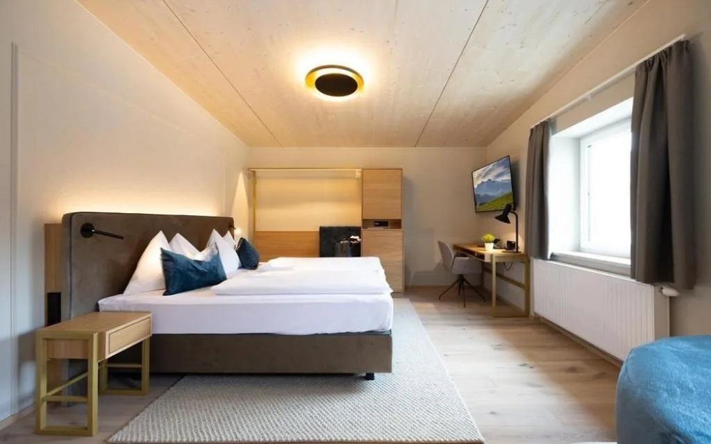 Camera con letto matrimoniale, soffitto in legno e TV a parete