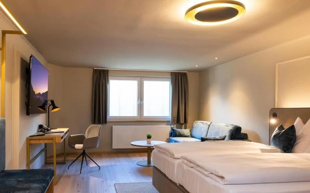 Camera luminosa con letto matrimoniale, divano blu e scrivania