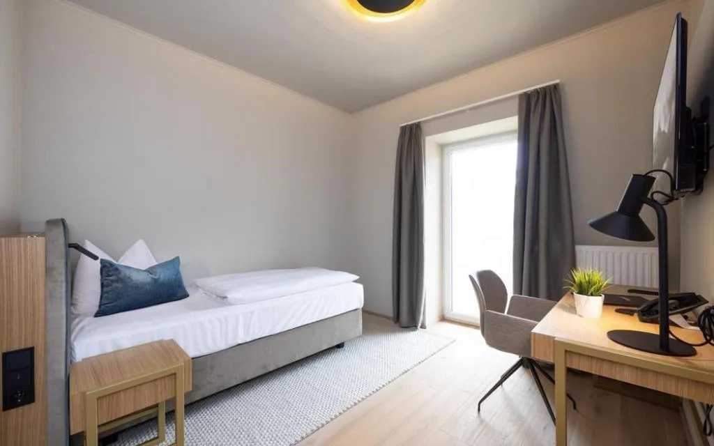 Camera singola essenziale con letto, scrivania e TV