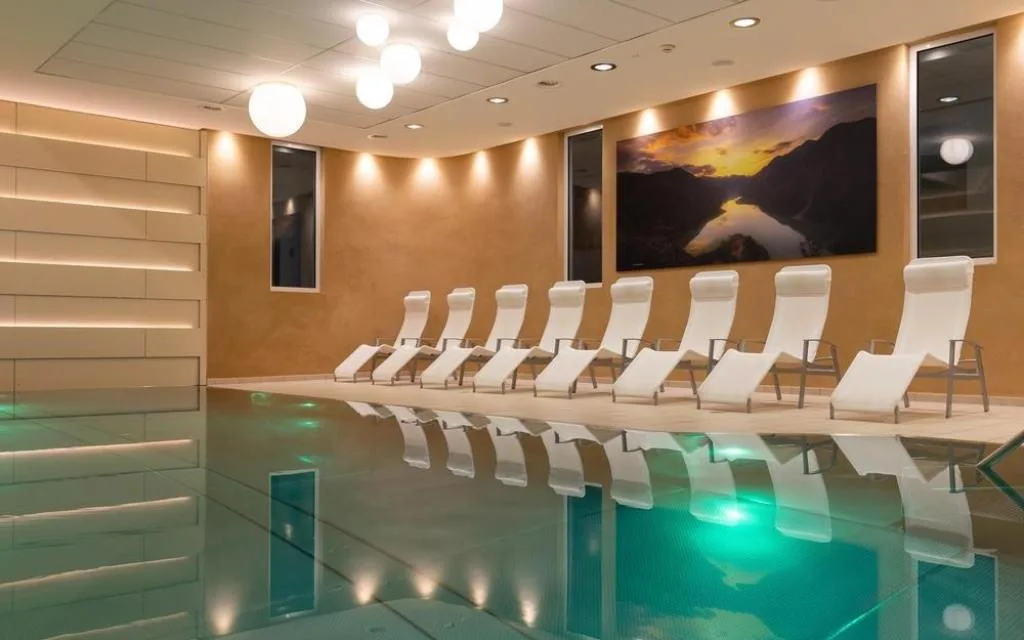 Piscina interna con lettini bianchi e illuminazione soffusa