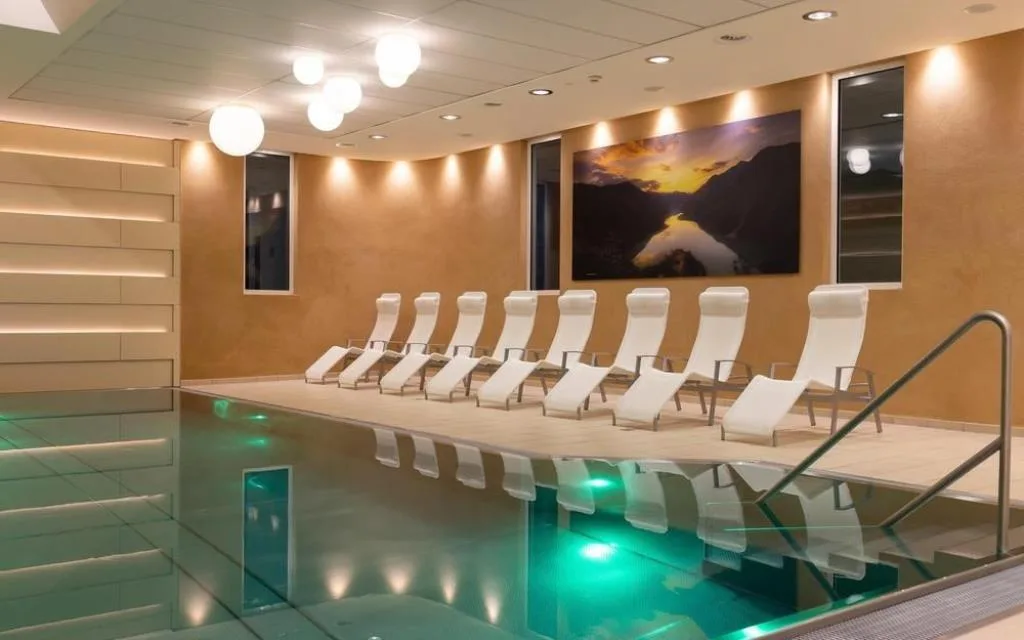 Piscina coperta con lettini bianchi allineati e quadro panoramico