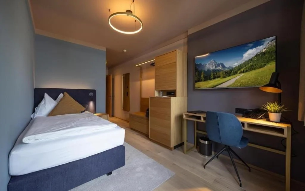Camera con letto singolo, scrivania e TV con vista montagne