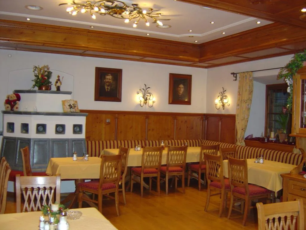 Accogliente sala ristorante con stufa in maiolica, boiserie in legno e panche a righe