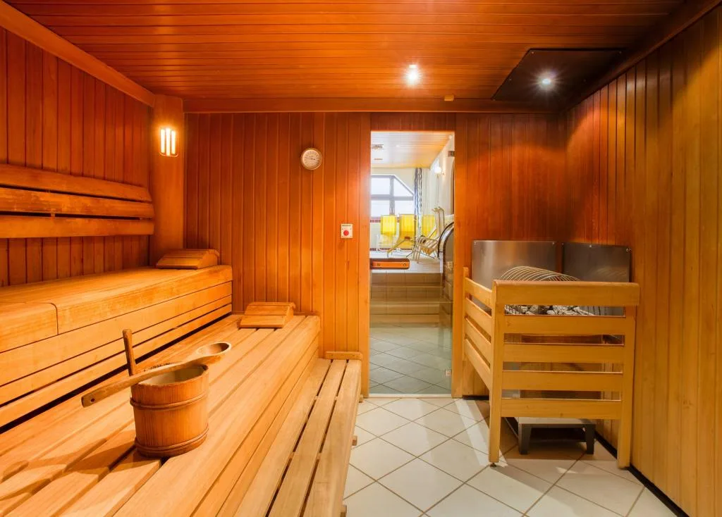Sauna finlandese in legno con panche e secchio tradizionale nella zona benessere