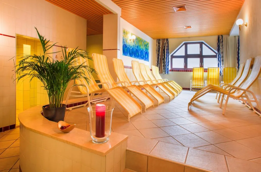 Zona relax della spa con lettini gialli, pavimento in piastrelle e pianta ornamentale