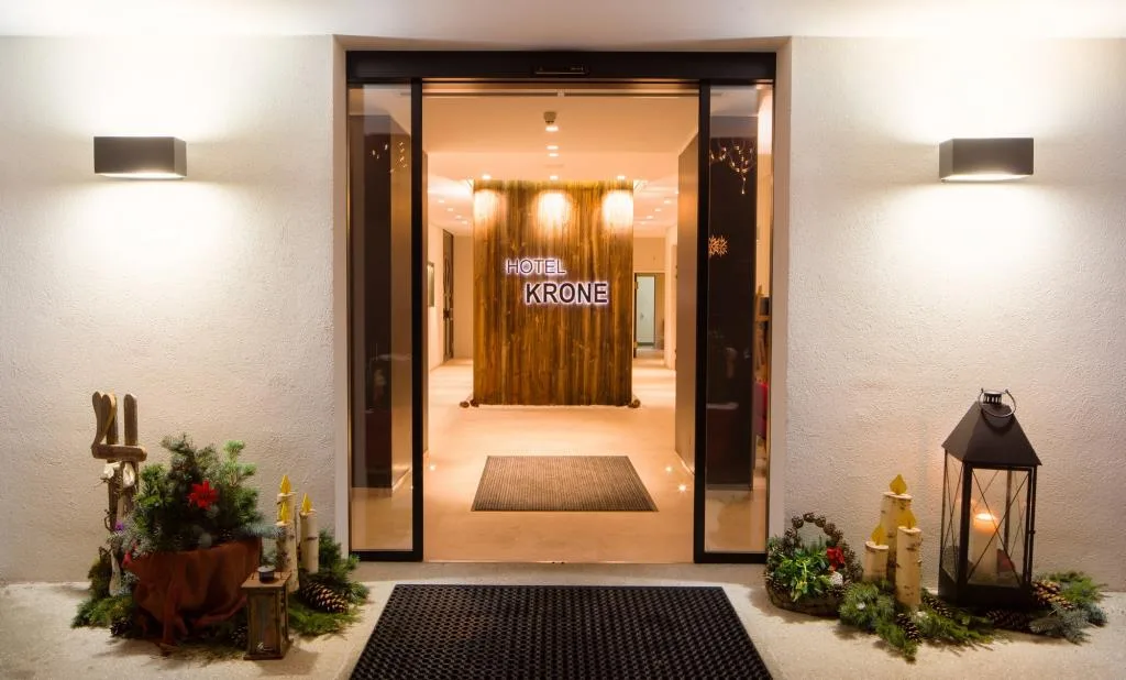 Ingresso illuminato dell'Hotel Krone con decorazioni natalizie e insegna luminosa