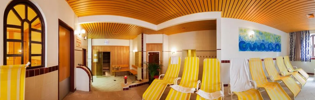 Area benessere panoramica con lettini gialli a righe e soffitto in legno