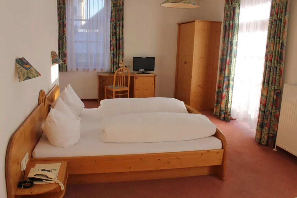 Camera doppia in stile classico con letto in legno di pino, scrivania e tende colorate