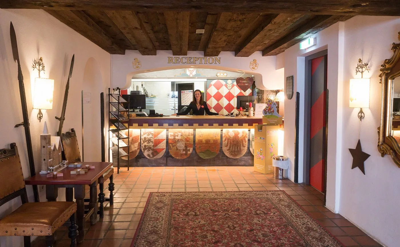Reception dell'hotel con decorazioni araldiche e receptionist