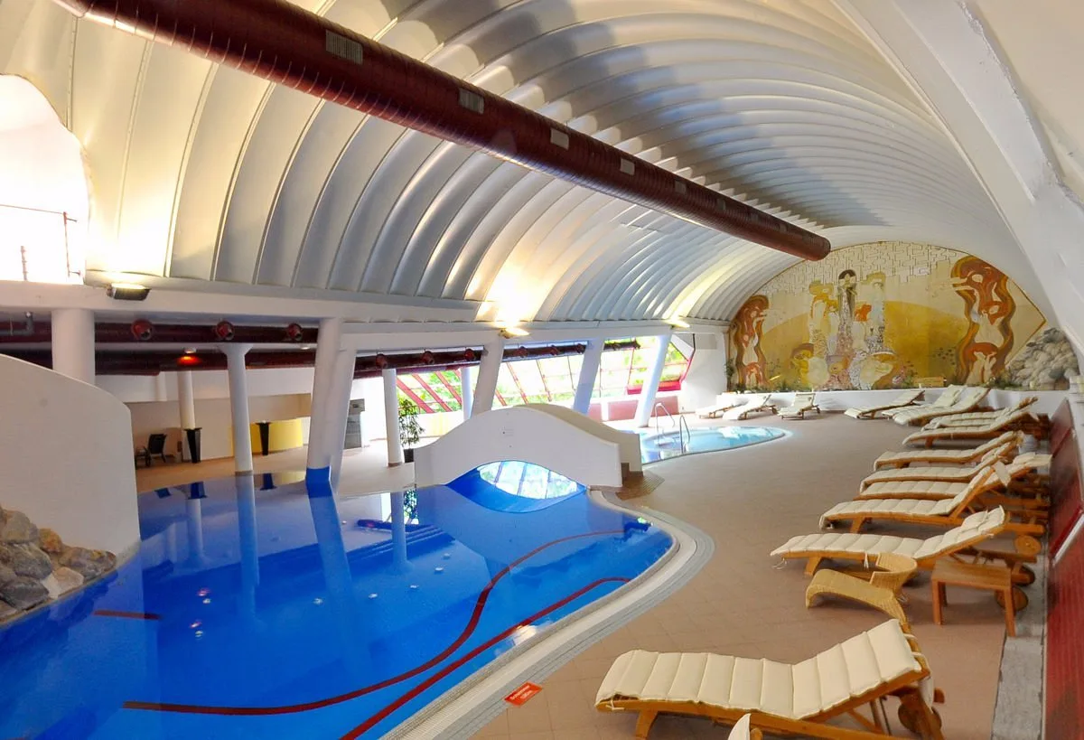 Piscina coperta con soffitto a volta, lettini e affresco a parete