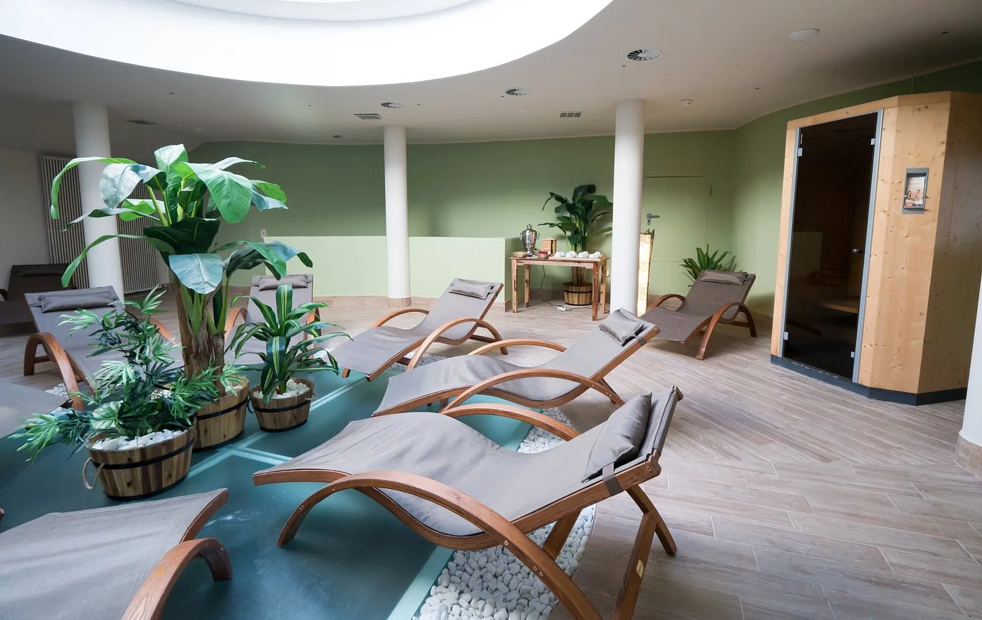 Zona relax della spa con lettini in legno, piante e sauna