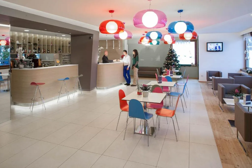 Hall dell'hotel con reception, lampadari colorati, tavolini e albero di Natale