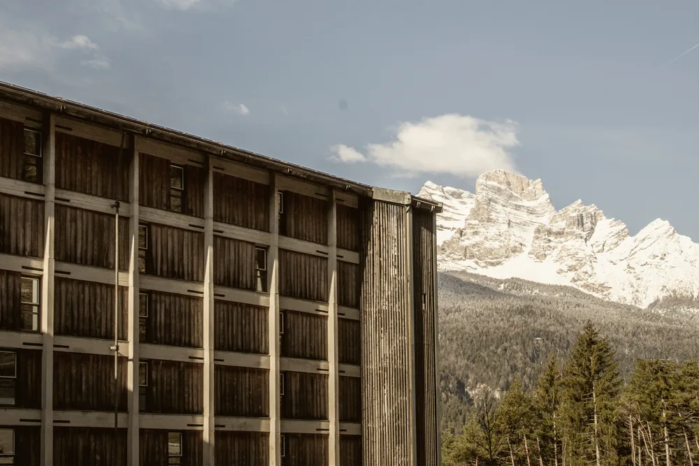 Facciata in legno dell'hotel con le cime innevate delle Dolomiti sullo sfondo