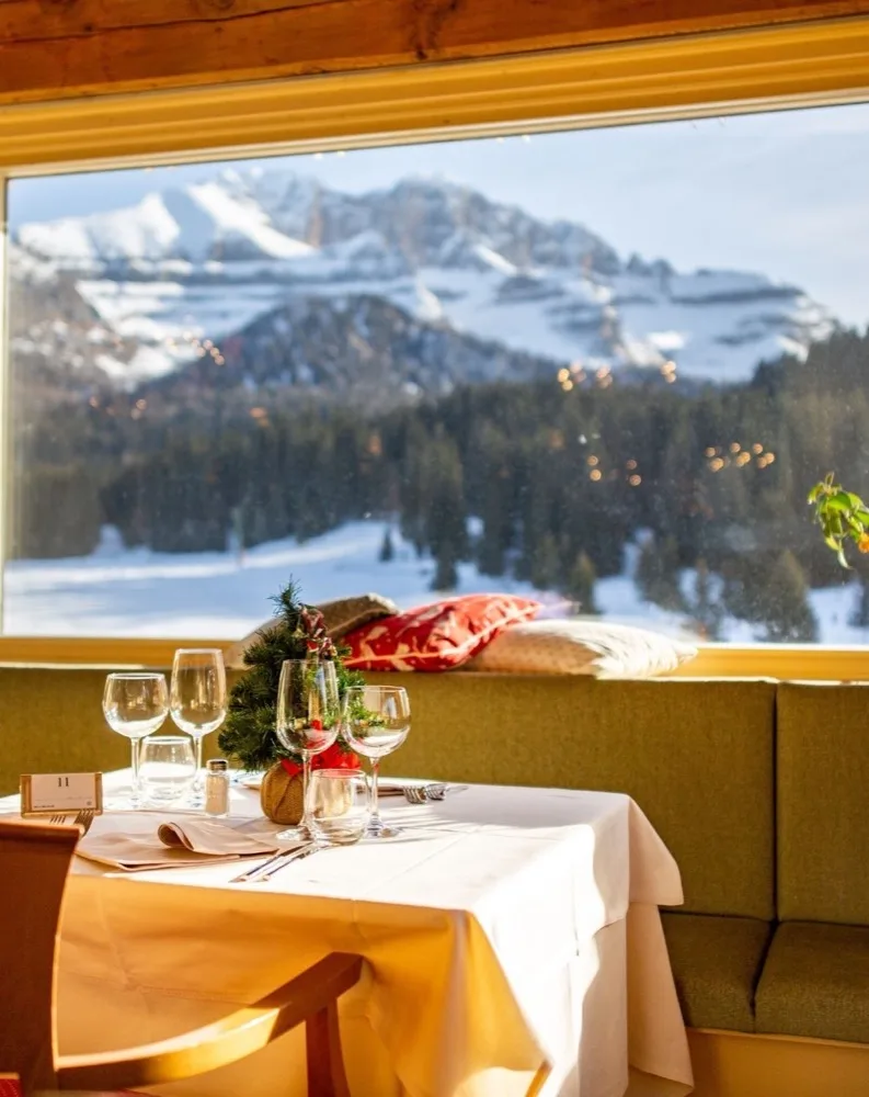 Tavolo del ristorante apparecchiato con vista sulle montagne innevate
