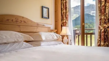Camera dell'hotel con letto matrimoniale e balcone vista montagne