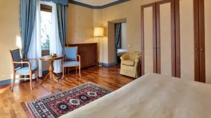 Camera elegante con parquet, poltrona e area soggiorno