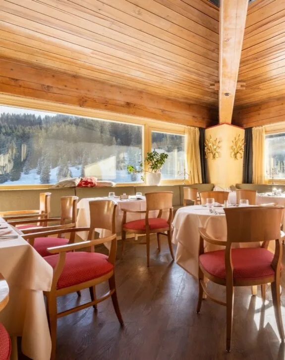 Sala da pranzo con soffitto in legno e vista sui boschi innevati