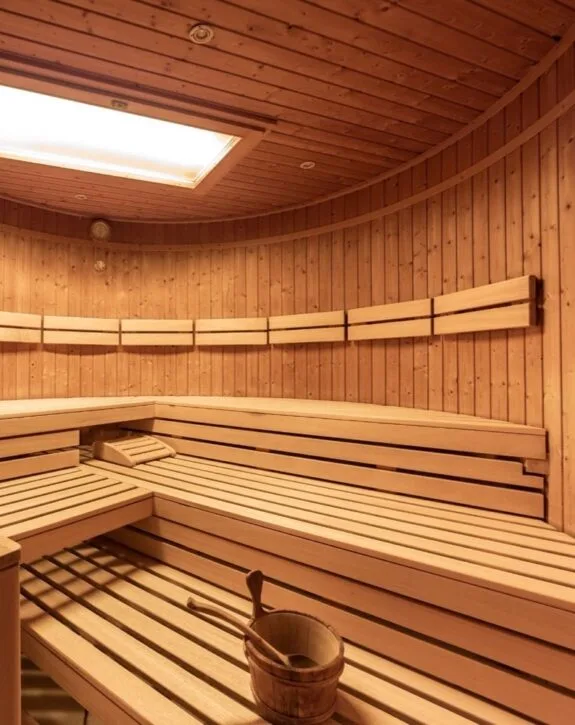Sauna finlandese in legno con panche e secchio tradizionale