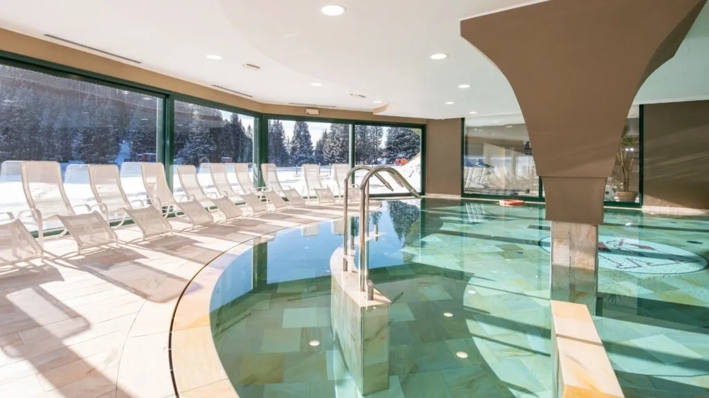 Piscina coperta con lettini e ampie vetrate sul paesaggio innevato
