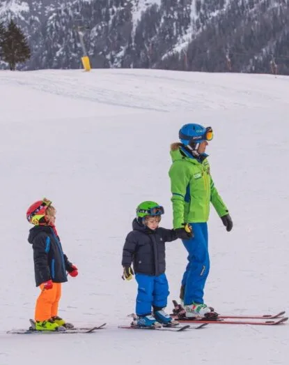 Maestro di sci con bambini durante una lezione sulla pista