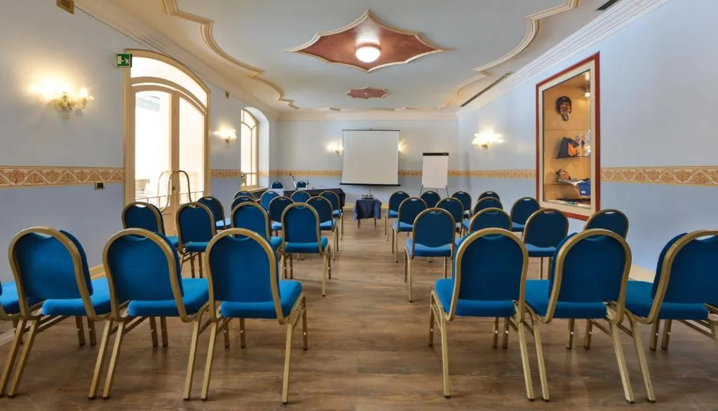 Sala meeting con sedie blu e schermo per proiezioni
