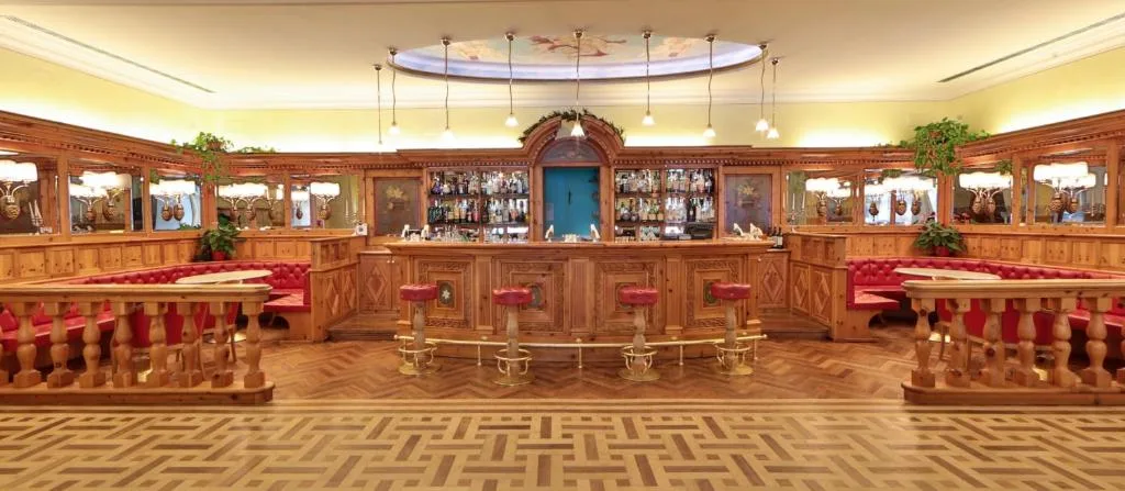 Bar dell'hotel in stile alpino con bancone in legno e sgabelli rossi