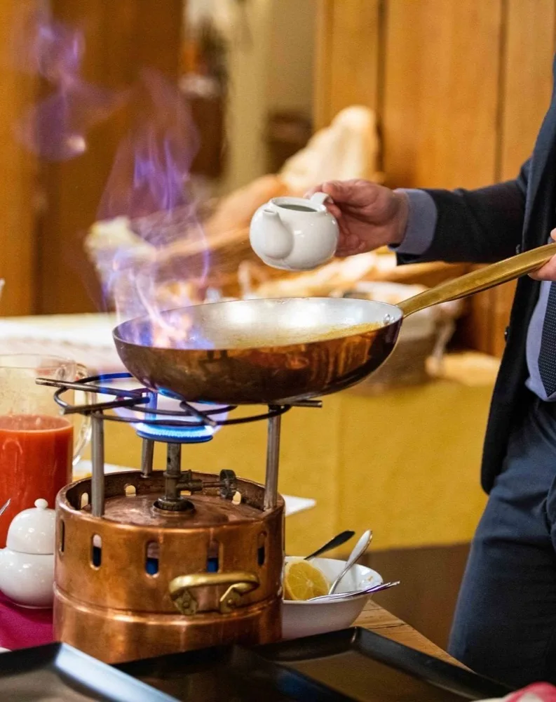 Preparazione di piatto flambé al tavolo con padella in rame