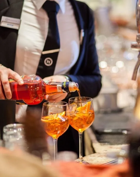 Barman prepara cocktail Aperol Spritz al bancone