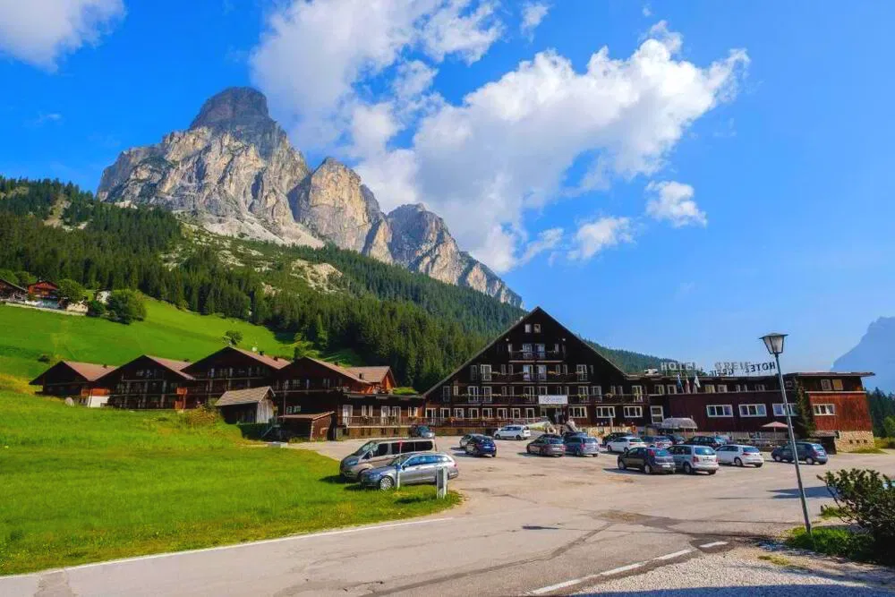 Vista estiva dell'hotel con prati verdi e montagne delle Dolomiti