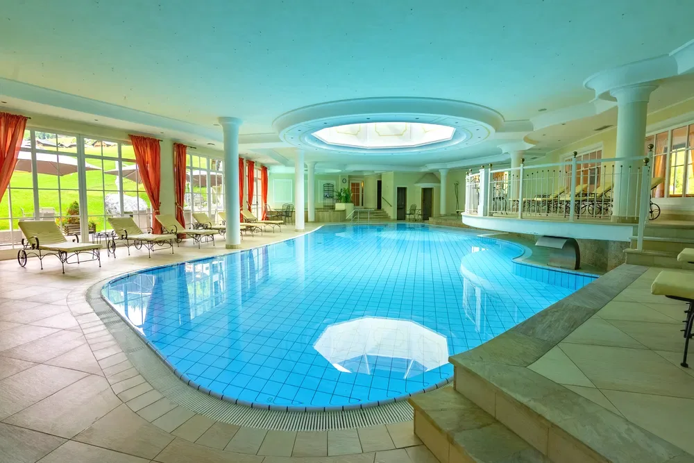 Piscina interna con colonne e vista sul giardino attraverso le vetrate