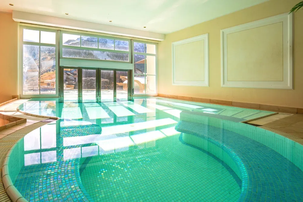 Piscina interna con mosaico verde e vista sulle montagne