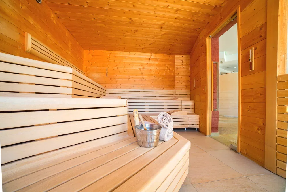 Sauna finlandese in legno con panche e secchiello