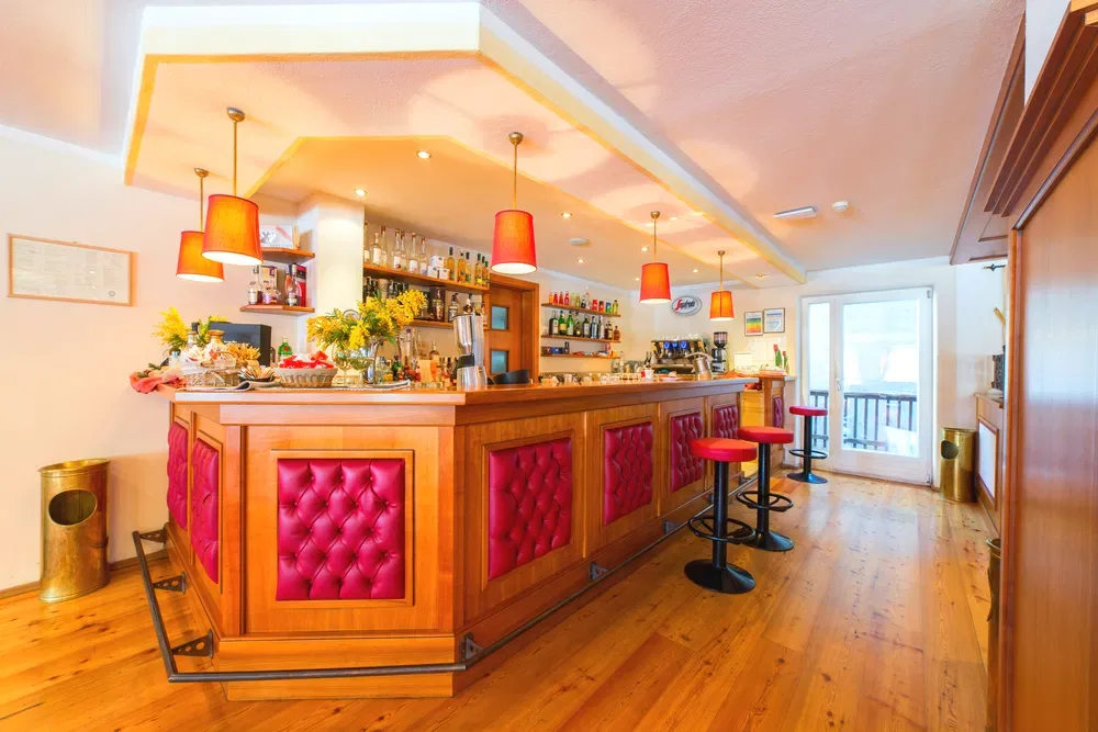 Bar dell'hotel con bancone in legno e sgabelli rossi