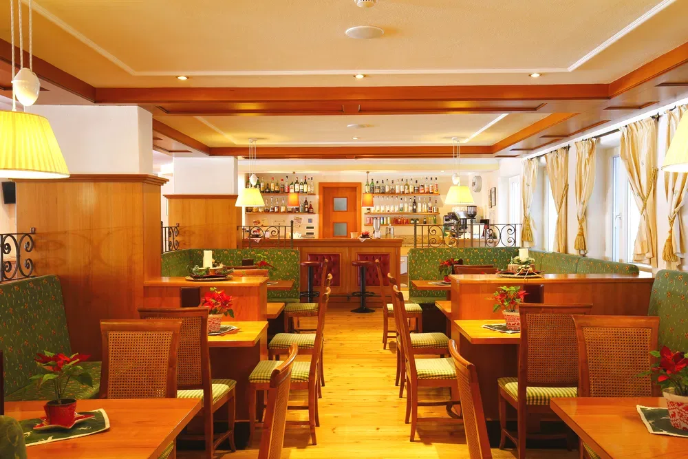 Sala ristorante in stile alpino con tavoli in legno e divanetti verdi