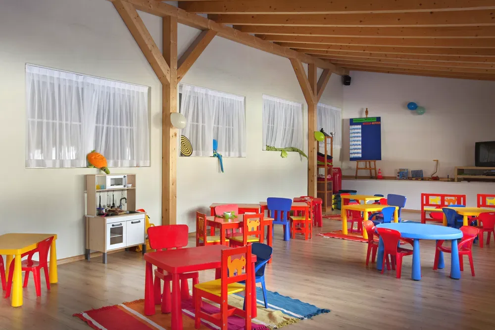 Area giochi per bambini con tavolini e sedie colorate