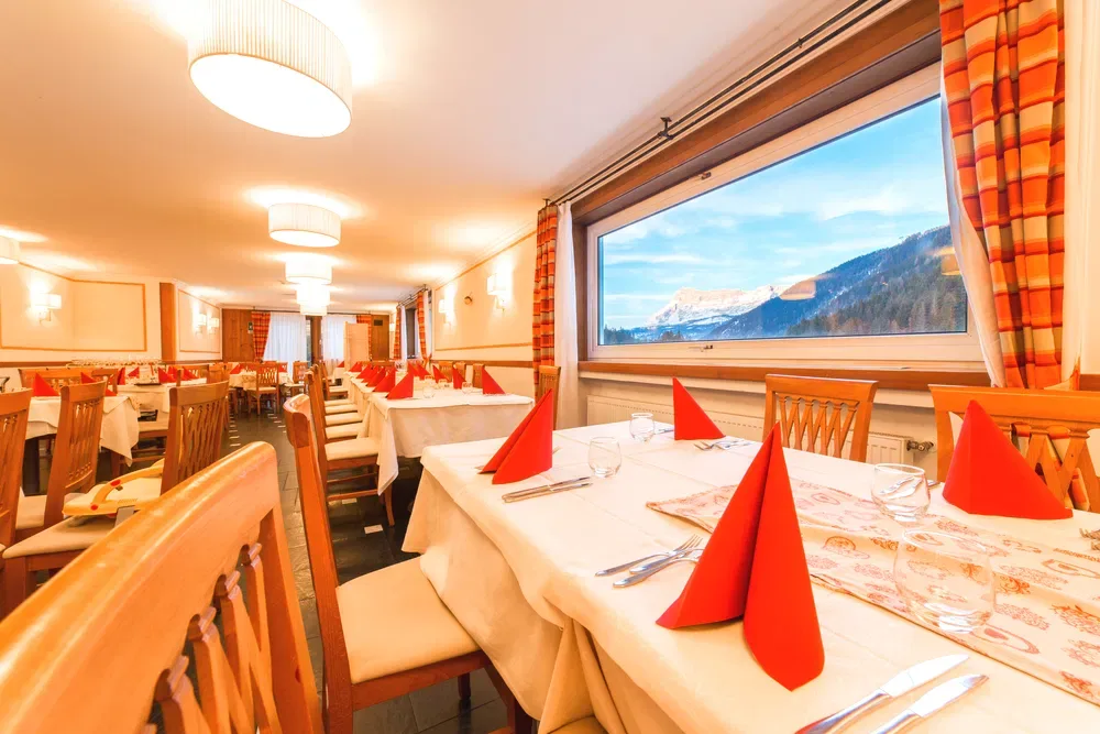 Ristorante con tavoli apparecchiati e ampia vetrata sulle montagne