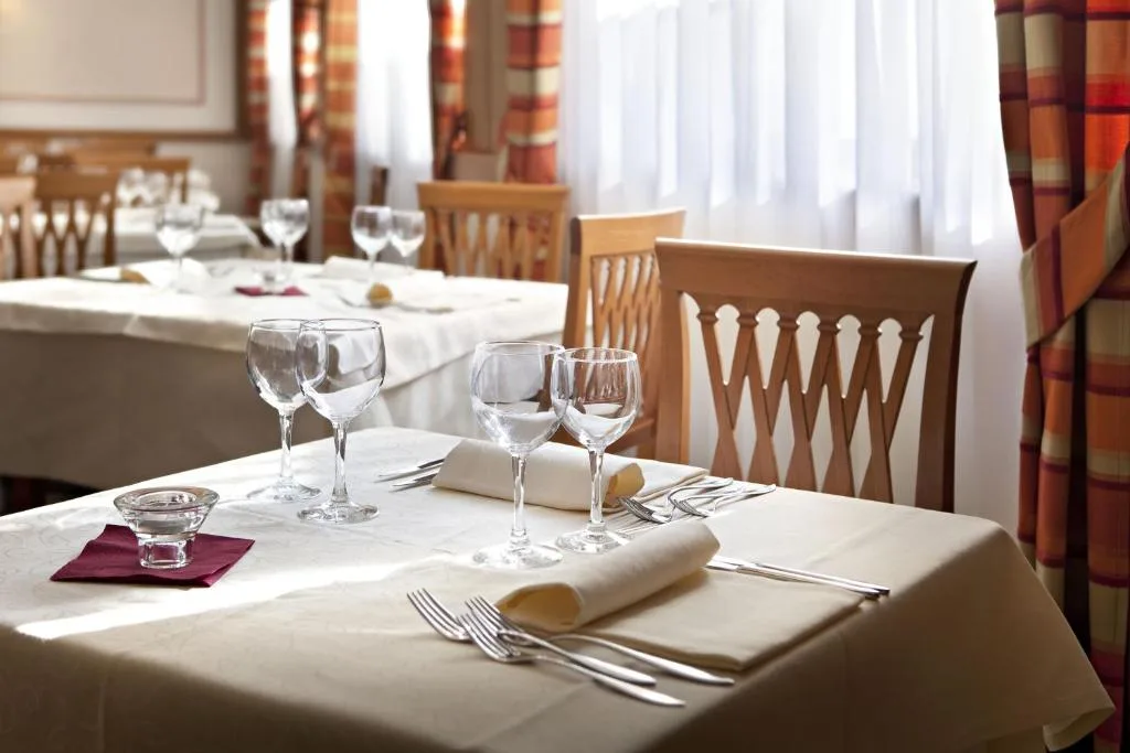 Tavolo del ristorante apparecchiato con calici e luce naturale
