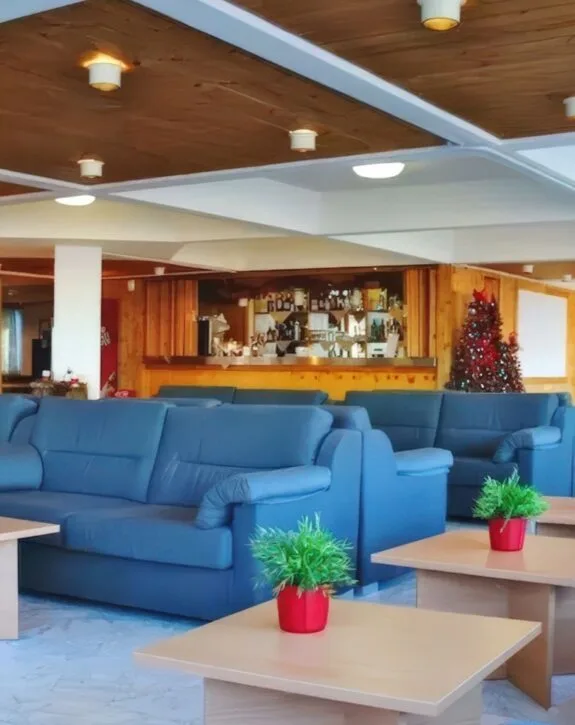 Zona relax con divani blu, bar in legno e albero di Natale addobbato