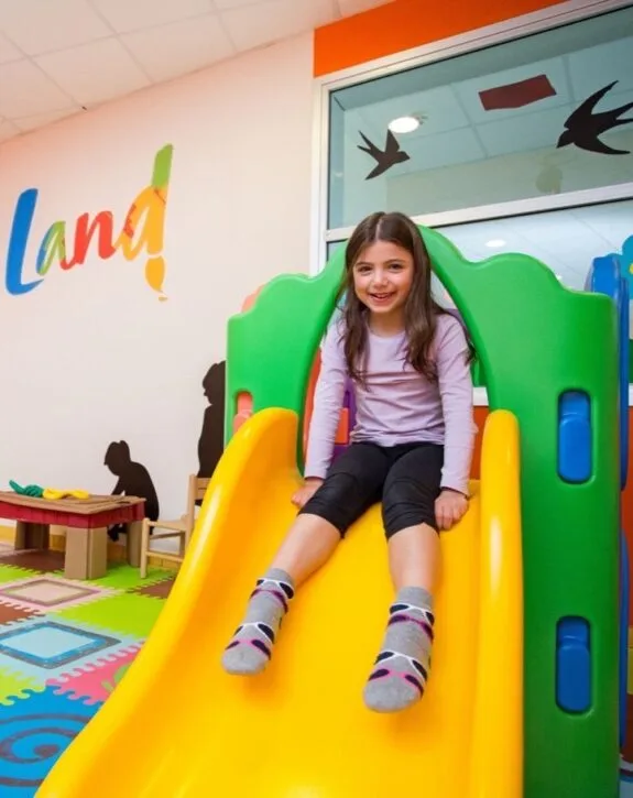 Bambina sorridente su uno scivolo colorato nell'area giochi per bambini