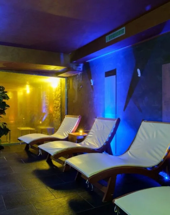 Area relax della spa con lettini e illuminazione soffusa blu e gialla