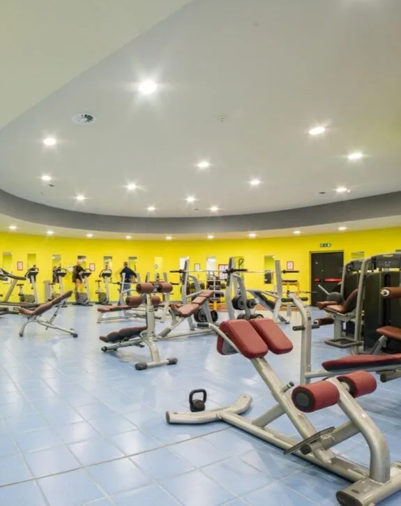 Sala fitness con attrezzature per allenamento e pareti gialle
