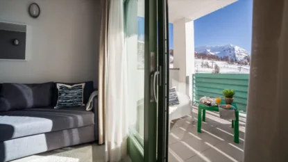 Soggiorno con divano e balcone affacciato su paesaggio innevato